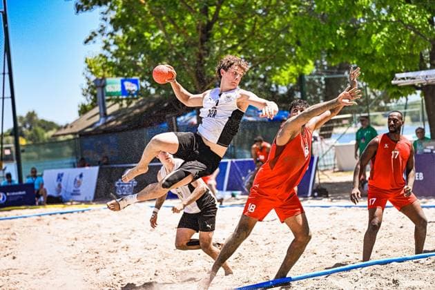 Ein Spieler der deutschen Beachhandball-Nationalmannschaft springt mit dem Ball zum Wurf ab, während zwei Gegenspieler in roten Trikots versuchen, den Abschluss zu blocken. Die Szene findet auf dem Sandplatz am Jarun See in Zagreb statt. IHF Beach Handball World Championship, WM, Weltmeisterschaft 2026, 23.06.2026, Zagreb, Jarun See *** A player on the German national beach handball team jumps up to shoot the ball, while two opponents in red jerseys try to block the shot. The scene takes place on the sand court at Lake Jarun in Zagreb. 2026 IHF Beach Handball World Championship, June 23, 2026, Zagreb, Lake Jarun Copyright: xspeedshotx xDorianfrickx