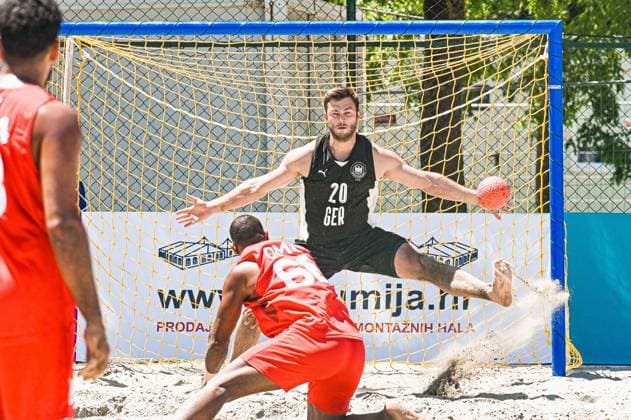 Oliver Middell ( 20; Deutschland Beachhandball Nationalmannschaft) streckt sich spektakulär im Tor und hält den Ball, während ein Angreifer im roten Trikot mit Sandaufwirbelung zum Wurf ansetzt. Die Szene findet am Jarun See in Zagreb statt. IHF Beach Handball World Championship, WM, Weltmeisterschaft 2026, 23.06.2026, Zagreb, Jarun See *** Oliver Middell 20: A player from the German national beach handball team stretches spectacularly in goal and blocks the ball, while an attacker in a red jersey prepares to shoot, kicking up a cloud of sand. The scene takes place at Lake Jarun in Zagreb during the 2026 IHF Beach Handball World Championship, June 23, 2026, Zagreb, Lake Jarun Copyright: xspeedshotx xDorianfrickx