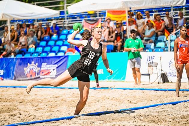 Pauline Borrmann ( 18; Deutsche Frauen Beachhandball Nationalmannschaft) holt im Sprung zum Wurf aus und hält den grünen Ball in der erhobenen Wurfhand. Im Hintergrund verfolgt eine Gegenspielerin der USA Women die Szene, während Zuschauer mit Deutschland-Fahnen die Tribüne füllen. IHF Beach Handball World Championship, WM, Weltmeisterschaft 2026, 23.06.2026, Zagreb, Jarun See *** Pauline Borrmann, 18, of the German Women’s Beach Handball National Team, winds up to take a shot and holds the green ball in her raised throwing hand. In the background, an opponent from the U.S. Women’s team watches the action, while spectators waving German flags fill the stands. IHF Beach Handball World Championship 2026, June 23, 2026, Zagreb, Lake Jarun Copyright: xspeedshotx xDorianfrickx