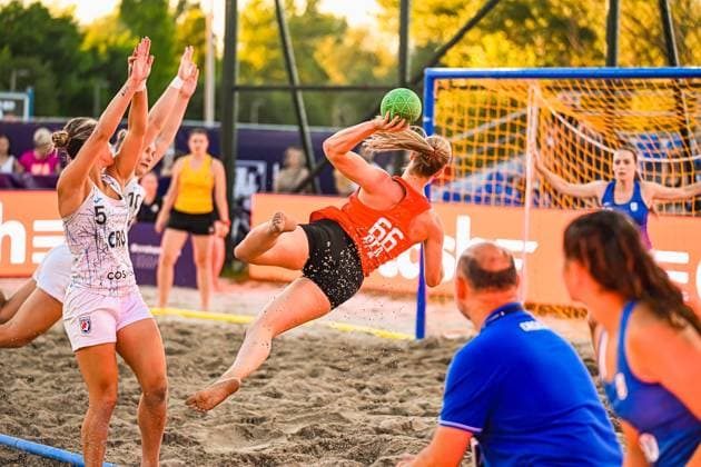 Eine Spielerin im orangefarbenen Trikot zieht aus dem Sand ab und wirft in spektakulärer Flugbewegung auf das Tor, während zwei kroatische Abwehrspielerinnen die Arme hochreißen. Im Hintergrund ist die Torhüterin in Abwehrstellung zu sehen. IHF Beach Handball World Championship, WM, Weltmeisterschaft 2026, 23.06.2026, Zagreb, Jarun See *** A player in an orange jersey takes off from the sand and makes a spectacular leap toward the goal, while two Croatian defenders throw their arms up. In the background, the goalkeeper can be seen in a defensive stance. IHF Beach Handball World Championship 2026, June 23, 2026, Zagreb, Lake Jarun Copyright: xspeedshotx xDorianfrickx