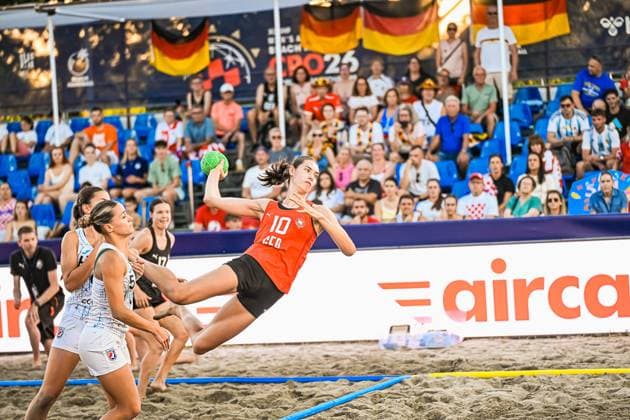 Isabel Kattner ( 10; Deutsche Frauen Beachhandball Nationalmannschaft) fliegt beim Sprungwurf durch die Luft und hält den grünen Ball in der Wurfhand, während zwei Spielerinnen der USA woman in der Abwehr stehen. Im Hintergrund verfolgen zahlreiche Zuschauer mit deutschen Fahnen das Spiel am Jarun See in Zagreb. IHF Beach Handball World Championship, WM, Weltmeisterschaft 2026, 23.06.2026, Zagreb, Jarun See *** Isabel Kattner, a member of the German women’s beach handball national team, leaps into the air and holds the green ball in her throwing hand, while two players from the U.S. women’s team stand in defense. In the background, numerous spectators waving German flags watch the game at Lake Jarun in Zagreb. IHF Beach Handball World Championship 2026, June 23, 2026, Zagreb, Lake Jarun Copyright: xspeedshotx xDorianfrickx