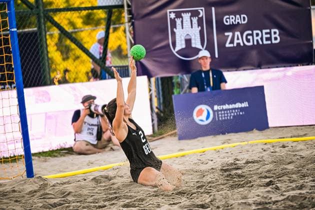 Joelle Arno ( 2; Deutsche Frauen Beachhandball Nationalmannschaft) wirft sich im Sand und streckt beide Arme zum grünen Ball, um einen Wurf zu parieren. Im Hintergrund ist das Banner der Stadt Zagreb sowie ein Fotograf am Spielfeldrand zu sehen. IHF Beach Handball World Championship, WM, Weltmeisterschaft 2026, 23.06.2026, Zagreb, Jarun See *** Joelle Arno 2 A player on the German women s national beach handball team throws herself onto the sand and stretches both arms toward the green ball to block a shot. In the background, the Zagreb city banner is visible, as well as a photographer on the sidelines. IHF Beach Handball World Championship 2026, June 23, 2026, Zagreb, Lake Jarun Copyright: xspeedshotx xDorianfrickx