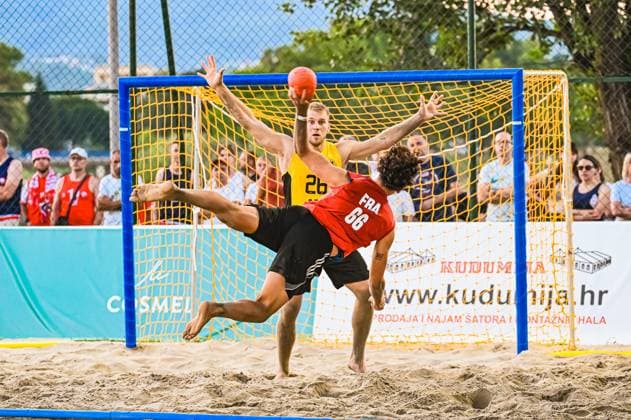 Moritz Ebert ( 26; Deutschland Beachhandball Nationalmannschaft) streckt sich im Tor, während ein französischer Angreifer ( 66) mit einem akrobatischen Fallwurf abschließt. Der Ball ist im Bild, die Szene zeigt den Höhepunkt der Wurfaktion vor Zuschauern am Jarun See in Zagreb. IHF Beach Handball World Championship, WM, Weltmeisterschaft 2026, 23.06.2026, Zagreb, Jarun See *** Moritz Ebert, 26, of the German national beach handball team, stretches out in goal, while a French attacker (No. 66) finishes with an acrobatic drop shot. The ball is in the frame; the scene captures the climax of the shot in front of spectators at Lake Jarun in Zagreb during the 2026 IHF Beach Handball World Championship, June 23, 2026, Zagreb, Lake Jarun Copyright: xspeedshotx xDorianfrickx