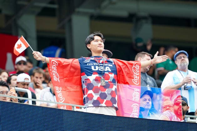 USA: Fußball FIFA World Cup, WM, Weltmeisterschaft, Fussball 2026, Sechzehntelfinale, Round of 32, Südafrika vs Kanada, South Africa vs Canada, SoFi Stadium (Inglewood, Los Angeles County, Kalifornien): Kanadischer Fußballfan breitet auf der Tribüne die Arme aus und schwenkt eine Kanada-Flagge. Über den Schultern trägt er eine rote Coca-Cola-Werbefahne wie einen Umhang. Fanporträt, Fankultur, Kanada, Nationalflagge, Zuschauer, Tribüne, Coca-Cola, Sponsor, Werbung, Werbemittel, FIFA World Cup 2026, WM 2026, Stadion, Emotion, Sportveranstaltung, Akkreditierung. *** USA Soccer FIFA World Cup 2026, Round of 32, South Africa vs. Canada, SoFi Stadium, Inglewood, Los Angeles County, California A Canadian soccer fan spreads his arms wide in the stands and waves a Canadian flag. Draped over his shoulders is a red Coca-Cola promotional banner, worn like a cape. Fan portrait, fan culture, Canada, national flag, spectator, stands, Coca-Cola, sponsor, advertising, promotional material, 2026 FIFA World Cup, 2026 World Cup, stadium, emotion, sporting event, accreditation Copyright: xJOERANxSTEINSIEKx