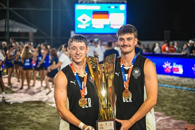 Zwei Spieler der deutschen Beachhandball-Nationalmannschaft halten gemeinsam den goldenen Siegerpokal und tragen Goldmedaillen um den Hals. Im Hintergrund ist die Anzeigetafel mit der deutschen Flagge sowie feiernde Zuschauer am Jarun See in Zagreb zu sehen. IHF Beach Handball World Championship, WM, Weltmeisterschaft 2026, 23.06.2026, Zagreb, Jarun See *** Two players from the German national beach handball team are holding the golden championship trophy together and wearing gold medals around their necks. In the background, the scoreboard with the German flag and celebrating spectators at Lake Jarun in Zagreb can be seen. IHF Beach Handball World Championship 2026, June 23, 2026, Zagreb, Lake Jarun Copyright: xspeedshotx xDorianfrickx