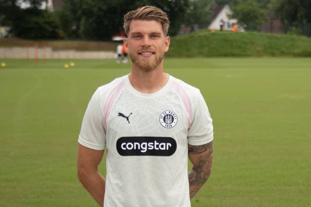 marcusmathisen vom FC St. Pauli steht lächelnd auf dem Trainingsplatz im Trainingszentrum in Hamburg. Er trägt das weiß-rosafarbene Puma-Trainingstrikot mit Congstar-Sponsoring und FC-St.-Pauli-Wappen. FC St. Pauli Spieler posiert beim Training in Hamburg *** Marcus Mathisen of FC St. Pauli stands smiling on the training field at the training center in Hamburg. He is wearing a white and pink Puma training jersey featuring Congstar sponsorship and the FC St. Pauli crest. An FC St. Pauli player poses during training in Hamburg. Copyright: xspeedshotx xAndreasxTolksdorfx