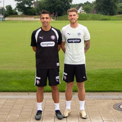 Trainer Rapp und Neuzugang Mathisen des FC St. Pauli stehen nebeneinander vor dem Trainingsplatz am Trainingszentrum in Hamburg. Beide tragen FC St. Pauli Trainingstrikots mit dem Congstar-Sponsorenlogo und lächeln in die Kamera. marcelrapp und marcusmathisen *** FC St. Pauli coach Rapp and new signing Mathisen stand side by side in front of the training field at the team s training center in Hamburg. Both are wearing FC St. Pauli training jerseys featuring the Congstar sponsor logo and are smiling at the camera. marcelrapp and marcusmathisen Copyright: xspeedshotx xAndreasxTolksdorfx