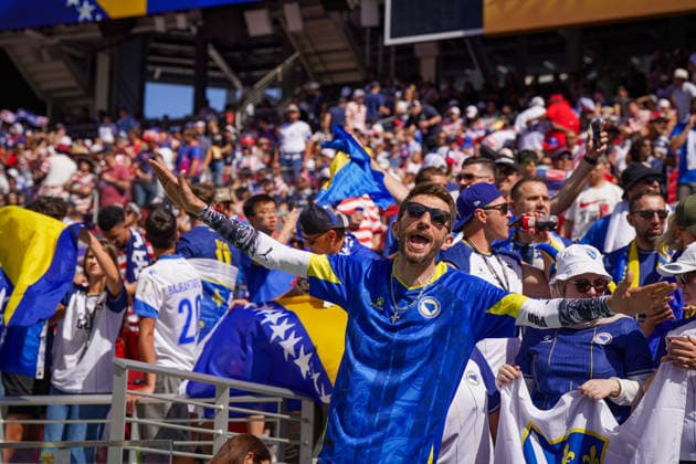 USA: Fußball FIFA World Cup, WM, Weltmeisterschaft, Fussball 2026, Sechzehntelfinale - USA vs Bosnien - Herzegowina im Levi™s Stadium (Santa Clara, San Francisco Bay Area, Kalifornien): Bosnische Fußballfans feiern auf der Tribüne vor dem Play-off-Spiel USA gegen Bosnien und Herzegowina. Fan im Trikot der Nationalmannschaft mit ausgebreiteten Armen, Fahnen von Bosnien und Herzegowina, Zuschauer, Fankultur, Emotionen, Jubel, Support, Tribüne, Stadionatmosphäre, Nationalfarben, Symbolbild. *** USA Soccer FIFA World Cup 2026, Round of 32: USA vs. Bosnia and Herzegovina at Levi’s Stadium in Santa Clara, San Francisco Bay Area, California. Bosnian soccer fans celebrate in the stands before the playoff match between the USA and Bosnia and Herzegovina. A fan wearing the national team jersey with arms outstretched, Bosnia and Herzegovina flags, spectators, fan culture, emotions, cheering, support, stands, stadium atmosphere, national colors, symbolic image Copyright: xJOERANxSTEINSIEKx
