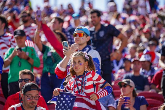 USA: Fußball FIFA World Cup, WM, Weltmeisterschaft, Fussball 2026, Sechzehntelfinale - USA vs Bosnien - Herzegowina im Levi™s Stadium (Santa Clara, San Francisco Bay Area, Kalifornien): Mädchen im USA-Trikot mit US-Flagge und Gesichtsbemalung verfolgt die FIFA Fußball-Weltmeisterschaft 2026 auf der Tribüne des Levi™s Stadium. Im Hintergrund zahlreiche US-Fans in Nationalfarben, Fahnen, Smartphones und Fanartikel. Fankultur, Porträt, Kinder, Familie, Zuschauer, Tribüne, USA, Patriotismus, Fußballbegeisterung, Sportstätte, Innenansicht, Stimmung, Großereignis. *** USA Soccer FIFA World Cup 2026, Round of 32: USA vs. Bosnia and Herzegovina at Levi’s Stadium in Santa Clara, San Francisco Bay Area, California. A girl wearing a USA jersey with a U.S. flag and face paint watches the 2026 FIFA World Cup from the stands at Levi’s Stadium. In the background, numerous U.S. fans in national colors, waving flags, holding smartphones, and wearing fan merchandise. Fan culture, portrait, children, family, spectators, Stands, USA, Patriotism, Soccer Enthusiasm, Sports Venue, Interior View, Atmosphere, Major Event Copyright: xJOERANxSTEINSIEKx