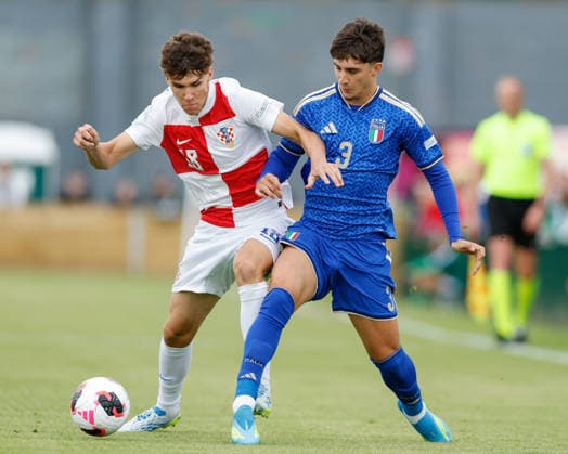 Caernarfon, Wales, 2nd July 2026. Pavle Smilajnic of Croatia (left) and Matteo Cocchi of Italy (right) battle for the ball during the Croatia U19 vs Italy U19 UEFA European U19 Championship match at The Oval, Caernarfon. Picture credit should read: Cody Froggatt Sportimage EDITORIAL USE ONLY. No use with unauthorised audio, video, data, fixture lists, club league logos or live services. Online in-match use limited to 120 images, no video emulation. No use in betting, games or single club league player publications. SPI_008_CF_CROATIA_U19_V_ITALY_U19 SPI-4850-0008