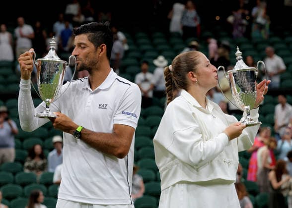 RECORD DATE NOT STATED 9th July 2026; All England Lawn Tennis and Croquet Club, London, England; Wimbledon Tennis Tournament, Day Eleven; Marcelo Arevalo (SLV) and mixed doubles partner Jelena Ostapenko (LAT) celebrate kissing their mixed doubles trophies after defeating Marc Polmans (AUS) and Storm Hunter (AUS) in the mixed doubles final JohnxPatrickxFletcher