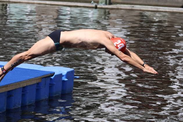 Ein Triathlet springt vom Startblock in die Binnenalster. Die rote Badekappe mit der Startnummer 12 ist deutlich sichtbar. Triathlet mit Startnummer 12 beim Schwimmstart in der Binnenalster *** A triathlete jumps from the starting block into the Binnenalster. The red swim cap with the number 12 is clearly visible. Triathlete with the number 12 at the start of the swim in the Binnenalster Copyright: xspeedshotx xSarahxWolfx
