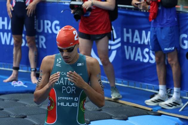 Ein Triathlet in Startnummer 2 atmet vordem Wettkampf durch, umgeben von Betreuern und Zuschauern an der Wechselzone. Die blaue Absperrung und das Hamburg-Branding kennzeichnen den Austragungsort Jungfernstieg, Miguel Hidalgo ( 2, Elite Männer) Triathlet vor dem Wettkampf an der Binnenalster Hamburg, Miguel Hidalgo 2 *** A triathlete wearing bib number 2 takes a deep breath before the race, surrounded by support staff and spectators in the transition area. The blue barrier and Hamburg branding mark the venue at Jungfernstieg, Miguel Hidalgo 2, Elite men’s triathlete before the race at the Binnenalster in Hamburg, Miguel Hidalgo 2 Copyright: xspeedshotx xSarahxWolfx