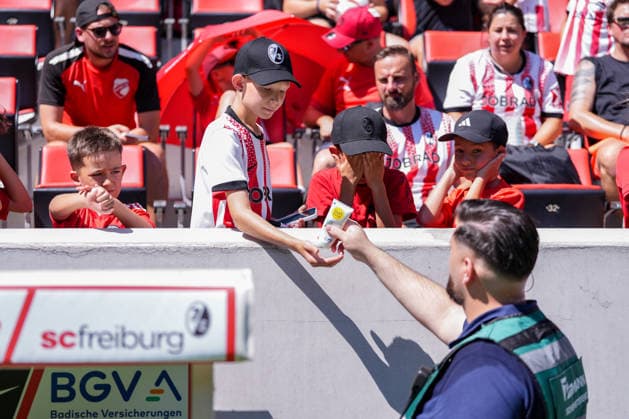 Ordner verteilt Sonnencreme, Sonne, Hitze, Sonnenschutz , Deutschland, Fussball, 1. Bundesliga, 2026 2027, SC Freiburg, Öffentliches Training, 12.07.2026, Europa-Park Stadion, Freiburg Freiburg Europa-Park Stadion Baden-Württemberg Deutschland *** Staff member handing out sunscreen, sun, heat, sun protection, Germany, soccer, Bundesliga 1, 2026–2027, SC Freiburg, public practice, July 12, 2026, Europa-Park Stadium, Freiburg, Freiburg, Europa-Park Stadium, Baden-Württemberg, Germany Copyright: xArnexAmbergx