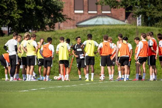 Ein Trainer hält mit Notizblatt in der Hand eine Ansprache an die versammelte Mannschaft des FC St. Pauli auf dem Trainingsplatz. Die Spieler tragen gelbe und orangefarbene Trainingsleibchen über weißen Trikots und hören aufmerksam zu. Marcel Rapp ( mr FC St. Pauli) gibt Anweisungen im Training *** A coach, holding a notepad, addresses the assembled FC St. Pauli team on the practice field. The players are wearing yellow and orange training vests over their white jerseys and are listening attentively as Marcel Rapp of FC St. Pauli gives instructions during practice. Copyright: xAndreasxTolksdorfx