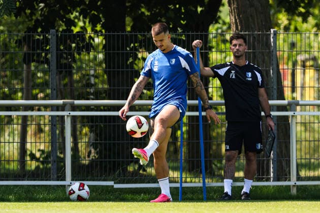 Mateusz Zukowski (1. FC Magdeburg,22) und im Hintergrund Athletiktrainer Felix Binsker (1. FC Magdeburg) - 2. Fußball Bundesliga Saison 2026-2027 Training 1. FC Magdeburg an der Avnet Arena in Magdeburg - Fußball,Mann,Männer,Deutschland,15.07.2026 *** Mateusz Zukowski, 1 FC Magdeburg, 22, with strength and conditioning coach Felix Binsker (1 FC Magdeburg) in the background; 2026–2027 Bundesliga season; 1 FC Magdeburg training session at the Avnet Arena in Magdeburg; soccer, man,Men, Germany, July 15, 2026