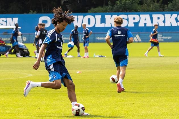 Ein Spieler des Hamburger SV kontrolliert den Ball beim Training auf dem Trainingsgelände am Volksparkstadion. Im Hintergrund sind weitere HSV-Spieler in dunkelblauen Trikots mit HanseMerkur-Sponsoring zu sehen. HSV-Spieler beim Balltraining am Volksparkstadion Hamburg *** A Hamburg SV player controls the ball during practice at the training facility at the Volksparkstadion. In the background, other HSV players can be seen wearing dark blue jerseys featuring HanseMerkur sponsorship. HSV players during ball practice at the Volksparkstadion in Hamburg Copyright: xspeedshotx xAndreasxTolksdorfx