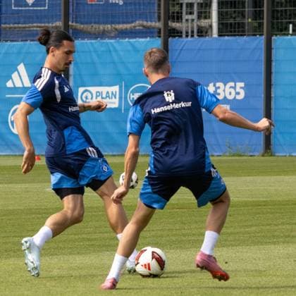 Zwei Spieler des Hamburger SV kämpfen beim Training am Volksparkstadion um den Ball. Der Spieler mit Haarknoten (Person A) steht dem Ball zugewandt, während sein Teamkollege von hinten heranläuft. Rayan Phillippe ( 14; Hamburger SV) im Zweikampf beim Training am Volksparkstadion *** Two Hamburger SV players battle for the ball during training at the Volksparkstadion. The player with the topknot, Person A, is facing the ball, while his teammate, Rayan Phillippe (No. 14, Hamburger SV), runs up from behind, engaging in a tackle during training at the Volksparkstadion. Copyright: xspeedshotx xAndreasxTolksdorfx