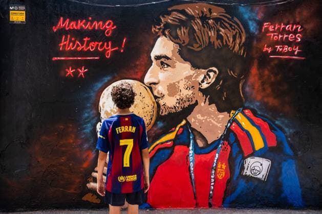 July 21, 2026, Barcelona, Spain: Locals enjoying the new fresh mural by Italian street artist TVBoy honoring FC Barcelona, Barca forward Ferran Torres wearing his Spain national team, Nationalteam jersey while holding the FIFA World Cup, WM, Weltmeisterschaft, Fussball Jules Rimet trophy is displayed on a street in central Barcelona. The artwork pays tribute to Torres after his extra-time winning goal against Argentina secured Spain s victory in the 2026 FIFA World Cup final onSunday July 19, 2026. Barcelona Spain - ZUMAq101 20260721_zna_q101_045 Copyright: xMarcxAsensioxClupesx