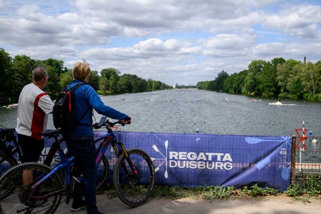 Blick auf die die Regattabahn Duisburg, vom Start aus, zwei Fahrradfahrer schauen sich die Wettkämpfe an, Banner Regatta Duisburg, am 23.07.2026 Rudern U-23 Weltmeisterschaft vom 23.07.- 26.07.2026 in Duisburg Deutschland. Regattabahn *** View of the Duisburg regatta course from the starting line; two cyclists are watching the races, Banner for the Duisburg Regatta, July 23, 2026: U23 World Rowing Championships, July 23–26, 2026, at the Duisburg Regatta Course in Germany