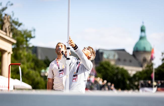 Deutsche Leichtathletik-Meisterschaften Stabhochsprung Männer; Hannover, 23.07.2026 Impression: Ein Kampfrichter kontrolliert die aktuelle Höhe der Stabhochsprunglatte. Im Hintergrund ist Moderator Tim Husel zu sehen; Deutsche Leichtathletik-Meisterschaften Stabhochsprung Männer am 23.07.2026 auf dem Opernplatz in Hannover (Niedersachsen). *** German Track and Field Championships—Men’s Pole Vault, Hanover, July 23, 2026: A judge checks the current height of the pole vault bar. Presenter Tim Husel can be seen in the background. German Track and Field Championships, Men’s Pole Vault, on July 23, 2026, at Opernplatz in Hanover, Lower Copyright: xBEAUTIFULxSPORTS R.xSchmittx