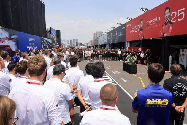 Mitglieder der FIA und FE Oragnistation sowie verschiedener Teams stehen um den Tisch mit dem Bild, Kerzen und Blumen in Gedenken an den kürzlich verstorbenen Cyril Blais (FRA) Teamchef vor der Citreon Box in der Boxengasse, FIA Formel E Weltmeisterschaft, Saison 12, Tokio E- Prix, 24.07.2026 *** Members of the FIA and FE organization, as well as various teams, stand around a table with a photo, candles, and flowers in memory of the recently deceased Cyril Blais, FRA team principal, in front of the Citroën pit in the pit lane, FIA Formula E World Championship, Season 12, Tokyo E-Prix, July 24, 2026