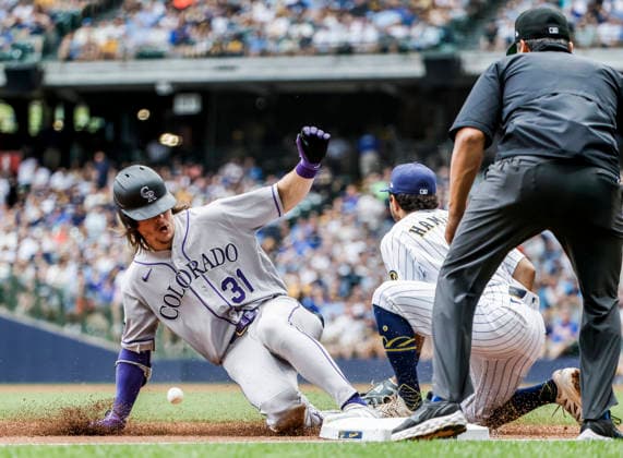 Colorado Rockies left fielder Jake McCarthy (L) slides into thrid base with a triple on Milwaukee Brewers third baseman David Hamilton (C) as third base umpire Charlie Ramos (R) watches in the third inning of the MLB, Baseball Herren, USA game between the Colorado Rockies and the Milwaukee Brewers at American Family Field in Milwaukee, Wisconsin on Friday July 24, 2026.  MIL20260724812 TANNENxMAURY