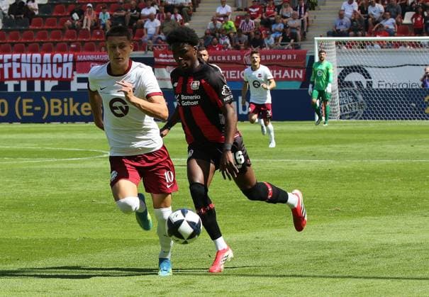 25.07.2026 xmgoodx Offenbach am Main, Plutos Stadion am Bieberer Berg - Jubiläumsspiel Kickers Offenbach (OFC) - Bayer 04 Leverkusen. Axel Tape (16, Leverkusen) gegen Jan Becker (10, OFC) fc *** July 25, 2026 xmgoodx Offenbach am Main, Pluto Stadium at Bieberer Berg Anniversary Match: Kickers Offenbach vs. OFC Bayer 04 Leverkusen Axel Tape 16, Leverkusen vs. Jan Becker 10, OFC fc
