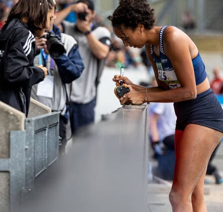 Deutsche Leichtathletik-Meisterschaften; Bochum-Wattenscheid, 26.07.2026 Malaika Mihambo (LG Kurpfalz) gibt einer Nachwuchsathletin ein Autogramm auf deren Spikes; Deutsche Leichtathletik-Meisterschaften am 26.07.2026 im Lohrheidestadion in Bochum-Wattenscheid (Nordrhein-Westfalen). *** German Track and Field Championships, Bochum-Wattenscheid, July 26, 2026: Malaika Mihambo of LG Kurpfalz signs an autograph on a young athlete’s spikes at the German Track and Field Championships on July 26, 2026, at Lohrheidestadion in Bochum-Wattenscheid, North Rhine-Westphalia Copyright: xBEAUTIFULxSPORTS R.xSchmittx
