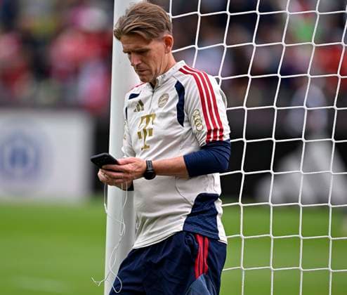 27.07.2026, Fussball Bundesliga 2026 2027, Trainingslager FC Bayern München in Rottach-Egern am Tegernsee (Bayern). Sportdirektor Christoph Freund (Bayern München) lehnt mit Handy am Pfosten *** July 27, 2026, 2026–2027 Bundesliga, FC Bayern Munich training camp in Rottach Egern on Lake Tegernsee; Bayern sporting director Christoph Freund; Bayern Munich player leans against the goalpost with his cell phone
