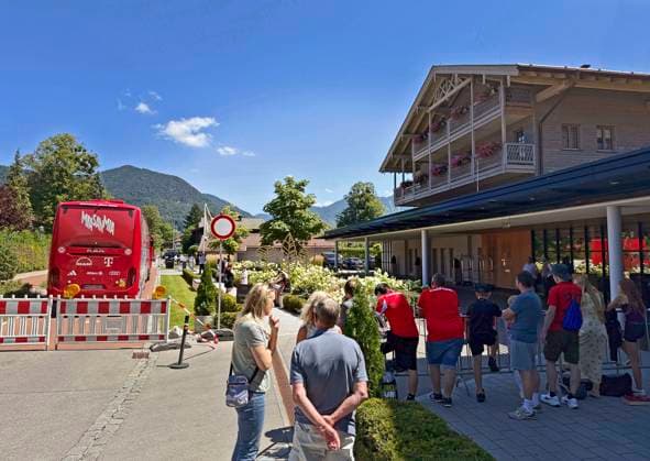 28.07.2026, Fussball Bundesliga 2026 2027, Trainingslager FC Bayern München in Rottach-Egern am Tegernsee (Bayern). Am Mannschaftshotel Parkhotel Egerner Höfe wurde eine Spur gesperrt für den parkenden Bayern-Mannschaftsbus, inklusive temporär aufgestellter Verkehrsampel. Bayernfans warten vor dem Hotel auf Autogramme ihrer Stars. *** July 28, 2026, 2026–2027 Bundesliga Season, FC Bayern Munich training camp in Rottach Egern on Lake Tegernsee, Bavaria. At the team hotel, Parkhotel Egerner Höfe, a lane was closed for the parked Bayern team bus, including a temporarily installed traffic light. Bayern fans wait in front of the hotel for autographs from their stars.