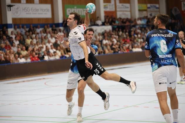 Ein Spieler der HSG Eider Harde springt zum Wurf und hält den Ball hoch, während Veron Na?inovi? ( 93; THW Kiel) im Hintergrund die Szene beobachtet. Harald Reinkind ( 6; THW Kiel) steht rechts im Bild, die Werner-Kuhrt-Halle in Hohn ist mit Zuschauern gefüllt. HSG Eider Harde Spieler beim Sprungwurf gegen Harald Reinkind ( 6; THW Kiel) *** A player from HSG Eider Harde jumps to take a shot and holds the ball aloft, while Veron Na inovi 93 of THW Kiel watches the action in the background; Harald Reinkind 6 of THW Kiel stands on the right side of the picture; the Werner Kuhrt Hall in Hohn is filled with spectators; an HSG Eider Harde player takes a jump shot against Harald Reinkind 6 of THW Kiel Copyright: xspeedshotx
