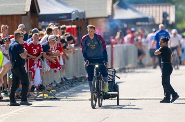 30.07.2026, Fussball Bundesliga 2026 2027, Trainingslager FC Bayern München in Rottach-Egern am Tegernsee (Bayern). Testspiel FC Rottach Egern - FC Bayern München, Torwart Manuel Neuer (FC Bayern München) kommt mit dem Bike und Kinderanhänger am Stadion an. *** July 30, 2026, 2026–2027 Bundesliga, FC Bayern Munich training camp in Rottach Egern on Lake Tegernsee, Bavaria; friendly match between FC Rottach Egern and FC Bayern Munich; goalkeeper Manuel Neuer of FC Bayern Munich arrives at the stadium by bike with a child trailer