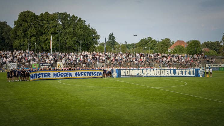 Fußball, Herren, Saison 2026 2027, Regionalliga Nordost, 2. Spieltag, SV Babelsberg 03 vs. FC Carl-Zeiss Jena, Freitag 31.07.2026, Karl-Liebknecht-Stadion, Im Bild: Die Fans des SV Babelsberg 03 und des FC Carl-Zeiss Jena setzen vor dem Spiel auf dem Platz des Karl-Liebknecht-Stadions ein klares Zeichen für die Aufstiegsreform. Meister müssen Aufsteigen Kompassmodell jetzt! Brandenburg Deutschland *** Soccer, Men s, 2026–2027 Season, Northeast Regional League, Matchday 2, SV Babelsberg 03 vs. FC Carl Zeiss Jena, Friday, July 31, 2026, Karl Liebknecht Stadium. Pictured: Fans of SV Babelsberg 03 and FC Carl Zeiss Jena send a clear message on the field at Karl Liebknecht Stadium before the game in support of promotion reform: Champions must be promoted—Compass Model now! Brandenburg, Germany
