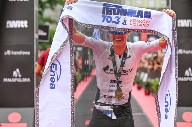 TRIATHLON: Stepniak And Bartlett Secure Elite Victories At IRONMAN 70.3 Krakow KRAKOW, POLAND - AUGUST 02: Professional triathlete Kacper Stepniak of Poland holds the official finish line banner over his head and smiles while wearing his winner s medal after winning the Enea IRONMAN 70.3 Krakow triathlon on the Main Market Square in Krakow, Lesser Poland Voivodeship, Poland, on August 02, 2026. Stepniak successfully defended his championship title, securing first place in the elite professional division with an official time of 3:36:37 following a 113-kilometer (70.3-mile) endurance race across the region. Krakow Poland  Copyright: xArturxWidakx originalFilename:widak-triathlo260802_np7lx.jpg