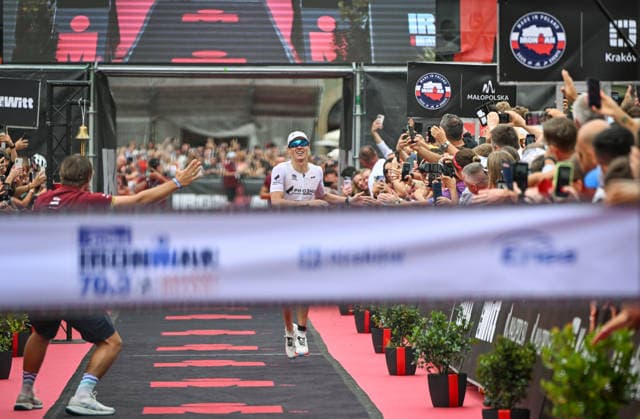 TRIATHLON: Stepniak And Bartlett Secure Elite Victories At IRONMAN 70.3 Krakow KRAKOW, POLAND - AUGUST 02: Professional triathlete Kacper Stepniak of Poland smiles and reaches out to high-five spectators as he approaches the finish line tape to win the Enea IRONMAN 70.3 Krakow triathlon on the Main Market Square in Krakow, Lesser Poland Voivodeship, Poland, on August 02, 2026. Stepniak successfully defended his home title, claiming victory in the elite professional field with a time of 3:36:37 after a close, race-long battle against Denmark s Daniel Baekkegard. Krakow Poland  Copyright: xArturxWidakx originalFilename:widak-triathlo260802_npf4r.jpg