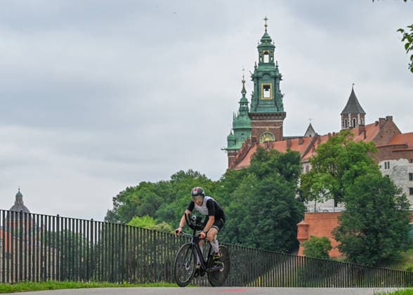 TRIATHLON: Stepniak And Bartlett Secure Elite Victories At IRONMAN 70.3 Krakow KRAKOW, POLAND - AUGUST 02: A triathlete corners tightly on his time-trial bicycle with the historic Wawel Royal Castle standing in the background during the 90-kilometer cycling segment of the Enea IRONMAN 70.3 Krakow triathlon in Krakow, Lesser Poland Voivodeship, Poland, on August 02, 2026. Over 2,100 competitors traversed the high-speed bike route flanking the city s historic landmarks before transitioning to the final half-marathon run. Krakow Poland  Copyright: xArturxWidakx originalFilename:widak-triathlo260802_np8t8.jpg