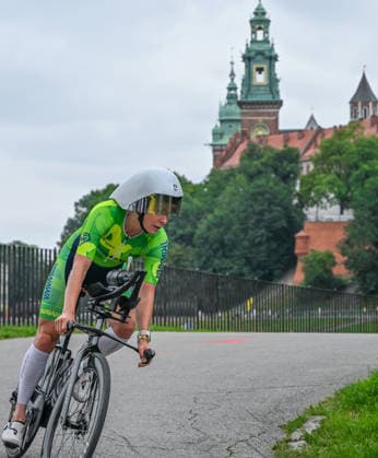 TRIATHLON: Stepniak And Bartlett Secure Elite Victories At IRONMAN 70.3 Krakow KRAKOW, POLAND - AUGUST 02: A female triathlete focuses intently on the road while leaning into a turn on her time-trial bicycle with Wawel Royal Castle in the background during the 90-kilometer bike segment of the Enea IRONMAN 70.3 Krakow triathlon in Krakow, Lesser Poland Voivodeship, Poland, on August 02, 2026. A field of over 2,100 registered competitors navigated the high-speed course looping through the region s historic landmarks before the final run discipline. Krakow Poland  Copyright: xArturxWidakx originalFilename:widak-triathlo260802_npfaG.jpg