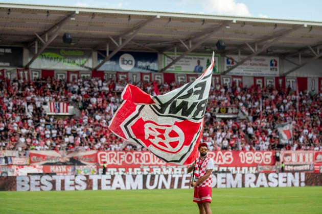 GER, Erfurt, Fussball, Regionalliga Nordost, 3. Spieltag, FC Rot-Weiss Erfurt vs. Tasmania Berlin im Bild v.l.: Fahnenschwenker mit Rot Weiss Erfurt Fahne in der Hand auf dem Spielfeld vor dem Spiel, im Hintergrund Steigerwaldkurve 05.08.2026, Steigerwaldstadion Erfurt DFB REGULATIONS PROHIBIT ANY USE OF PHOTOGRAPHS AS IMAGE SEQUENCES AND OR QUASI-VIDEO, *** GER, Erfurt, Soccer, Northeast Regional League, Matchday 3, FC Rot Weiss Erfurt vs. Tasmania Berlin: Pictured, from left, a flag-waver holding a Rot Weiss Erfurt flag on the field before the game; in the background, the Steigerwaldkurve, August 5, 2026, Steigerwald Stadium, Erfurt. DFB regulations prohibit any use of photographs as image sequences and or quasi-video, Copyright: HMBxMedia PaulxFritz