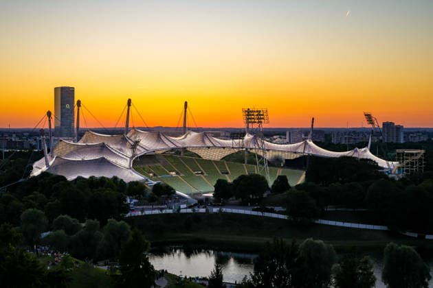 Ein Blick über den Münchner Olympiasee hin zum weltberühmten Olympiastadion bei Sonnenuntergang The iconic, tent-like roof structure glows in the evening light (License=RF) 25350602 Copyright: xZoonar.com SandraAlkadox 25350602