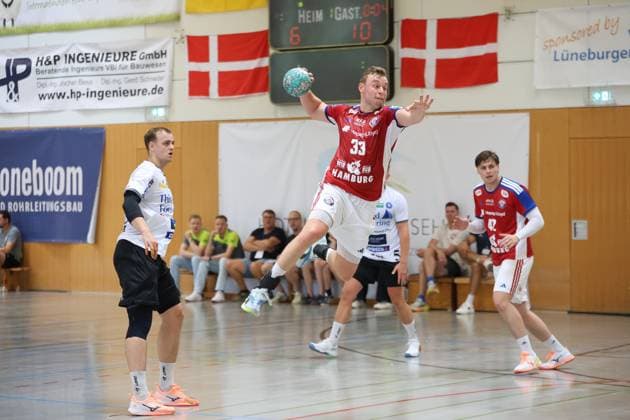 Moritz Sauter ( 33; HSV Hamburg) springt mit dem Ball in der Hand zum Wurf ab, während Jan Christian Schmidt im Hintergrund die Szene beobachtet. Auf der Anzeigetafel steht es 6:10 für den Gast. Moritz Sauter ( 33; HSV Hamburg) beim Sprungwurf in Schneverdingen *** Moritz Sauter (No. 33, HSV Hamburg) jumps to take a shot with the ball in his hand, while Jan Christian Schmidt watches the action in the background. The scoreboard reads 6–10 in favor of the visiting team. Moritz Sauter (No. 33, HSV Hamburg) takes a jump shot in Schneverdingen. Copyright: xspeedshotx