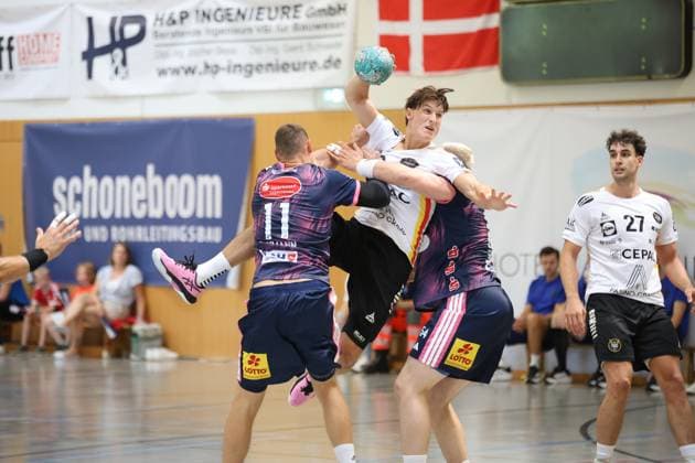 Ein PAUC-Handball-Spieler zieht im Sprung ab und wird dabei von zwei Abwehrspielern des TSV Hannover-Burgdorf ( 11) geblockt. Nikoloz Kalandadze ( 27; PAUC Handball) verfolgt die Szene aus dem Hintergrund. Nikoloz Kalandadze ( 27; PAUC Handball) beobachtet Wurfaktion im Zweikampf *** A PAUC Handball player takes a shot while jumping and is blocked by two defenders from TSV Hannover Burgdorf 11. Nikoloz Kalandadze (27), PAUC Handball, watches the play from the background. Nikoloz Kalandadze (27), PAUC Handball, watches the shot being taken during a one-on-one situation. Copyright: xspeedshotx