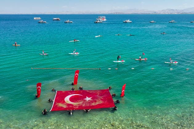 12th Van Sea Water Sports Festival kicks off on Lake Van VAN, TURKIYE - AUGUST 08: An aerial view of divers unfurling a large Turkish flag as participants and athletes taking part in the 12th Van Sea Water Sports Festival held at the Edremit-Gebze Water Sports Center on the shores of Lake Van in Van, Turkiye, on August 08, 2026. Organized to promote Lake Van and boost local tourism, the two-day event features Beach volleyball, Beachvolleyball and handball matches, flyboard demonstrations, canoeing, rowing, dragon boat races, and various recreational activities. Ozkan Bilgin Anadolu Van Turkey. Editorial use only. Please get in touch for any other usage.  Copyright: x2026xAnadoluxOzkanxBilginx