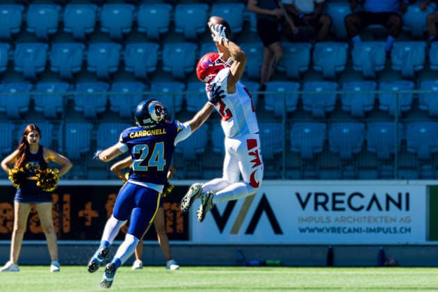 Alpine Rams defender Brayan Carbonell ( 24) leaps to defend a pass attempt as an airborne Firenze Red Lions Michele Costa ( 82)player reaches to secure the catch. The play takes place along the sideline during live game action. Cheerleaders and stadium seating are visible in the background on the artificial turf field. Alpine Rams vs Firenze Red Lions, American Football, American Football League Europe, Week 12, 2026, 8.8.2026, Copyright: xPFA RicoxDoninellix