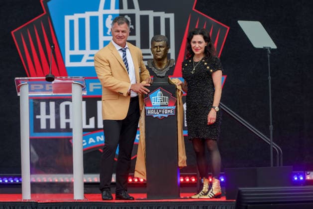 August 8, 2026: Adam Vinatieri, along with Colt co-owner and CEO Carlie Irsay-Gordon, pose for a picture with his Hall of Fame bust during the NFL, American Football Herren, USA Hall of Fame Enshrinement Ceremony at the Tom Benson Hall of Fame Stadium in Canton, OH. CSM Canton USA - ZUMAc04_ 20260808_zma_c04_219 Copyright: xJonathanxMailhesx
