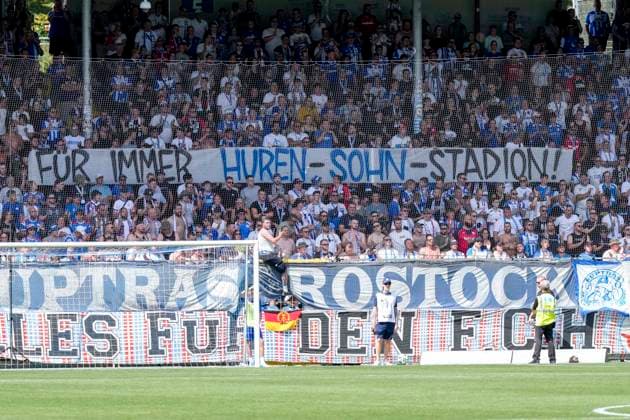 Die Fans vom F.C. Hansa Rostock zeigen in der Fankurve ein Banner, Spruchband mit der Aufschrift: Für immer Huren-Sohn-Stadion, Hurensohn, Fans, Ultras Publikum, Zuschauer, Stimmung, Atmosphäre, Stadion, Protest gegen Dietmar Hopp (Mitbegründer SAP, Mäzen, Investor, Förderer, Gesellschafter TSG 1899 Hoffenheim) und das nach ihm benannte Dietmar-Hopp-Stadion, Protestaktion, protestieren, Aktion, Action, 09.08.2026, Sinsheim (Deutschland), Fussball, 3. Liga, TSG 1899 Hoffenheim II - Hansa Rostock, DFB DFL REGULATIONS PROHIBIT ANY USE OF PHOTOGRAPHS AS IMAGE SEQUENCES AND OR QUASI-VIDEO. *** Fans of F.C. Hansa Rostock display a banner in the fan section that reads Forever Son of a Bitch Stadium, Son of a Bitch, fans, ultras, crowd, spectators, mood, atmosphere, stadium, protest against Dietmar Hopp, co-founder of SAP, patron, investor, sponsor, and shareholder of TSG 1899 Hoffenheim and the Dietmar Hopp Stadium named after him, protest action, protesting, action, August 9, 2026, Sinsheim, Germany, soccer, 3rd Division, TSG 1899 Hoffenheim II vs. Hansa Rostock, DFB and DFL regulations prohibit any use of photographs as image sequences and or quasi-video xozx