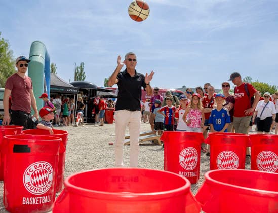 09.08.2026, Google Pixel Frauen-Bundesliga: Testspiel FC Bayern Frauen - Paris FC, im Sportpark Unterhaching, Fanfest vor dem Stadion, Präsident Herbert Hainer ( FC Bayern) macht einen Ballwurf in die Plastiktonnen bei den Basketballern am Stand *** August 9, 2026, Google Pixel Women s Bundesliga Friendly Match: FC Bayern Women vs. Paris FC, at Sportpark Unterhaching; fan festival in front of the stadium; FC Bayern President Herbert Hainer throws a ball into the plastic bins at the basketball team s booth