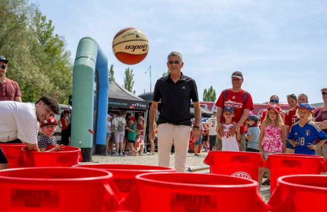 09.08.2026, Google Pixel Frauen-Bundesliga: Testspiel FC Bayern Frauen - Paris FC, im Sportpark Unterhaching, Fanfest vor dem Stadion, Präsident Herbert Hainer ( FC Bayern) macht einen Ballwurf in die Plastiktonnen bei den Basketballern am Stand *** August 9, 2026, Google Pixel Women s Bundesliga Friendly Match: FC Bayern Women vs. Paris FC, at Sportpark Unterhaching; fan festival in front of the stadium; FC Bayern President Herbert Hainer throws a ball into the plastic bins at the basketball team s booth