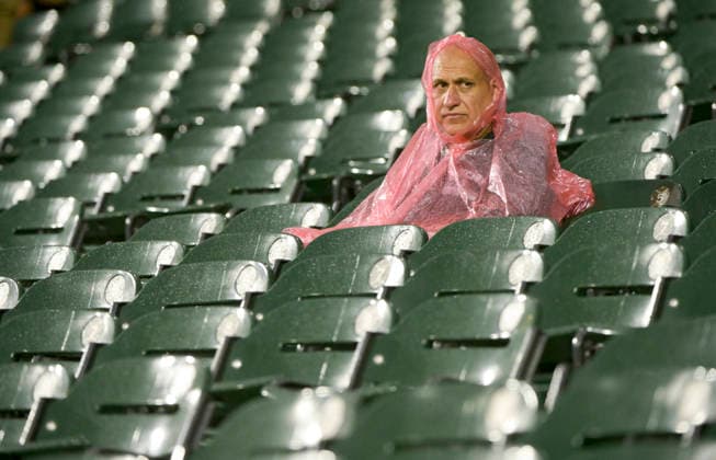 A spectator sits in the rain during the rain delay between the 1st and 2nd inning of the Chicago White Sox game against Cleveland Guardians at Rate Field in Chicago, IL on Sunday, August 9, 2026.  CHI20260809113 MARKxBLACK