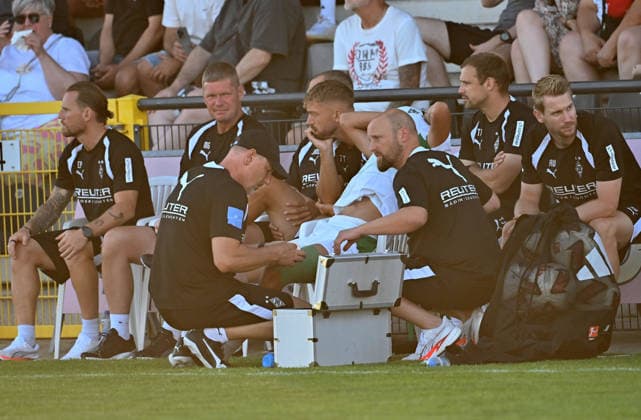 12.08.2026; Velbert; Fussball, Herren, Saison 2026 2027, Testspiel SSVg Velbert vs. Borussia Moenchengladbach Wael Mohya (Gladbach) sitzt verletzt auf der Bank und hat sich das Trikot ueber den Kopf gezogen. Dirk Mueller (Physiotherpeut Gladbach, li.) und Nils Haupt (Mannschaftsarzt Gladbach, re.) kuemmern sich um ihn DFL regulations prohibit any use of photographs as image sequences and or quasi-video. IMS Arena Nordrhein-Westfalen Deutschland *** August 12, 2026 Velbert Soccer, Men s, 2026–2027 Season, Friendly Match: SSVg Velbert vs. Borussia Mönchengladbach. Wael Mohya of Gladbach is sitting on the bench injured and has pulled his jersey over his head. Dirk Mueller, Gladbach’s physical therapist, left, and Nils Haupt, Gladbach’s team doctor, right, are taking care of him. DFL regulations prohibit any use of photographs as image sequences and or quasi-video. IMS Arena, North Rhine-Westphalia, Germany